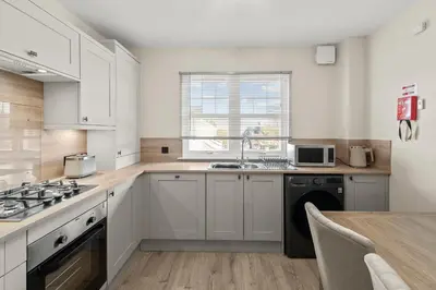a kitchen with white cabinets and a sink and a table at The Riverside Rest 2 in Stirling