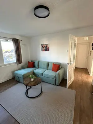 a living room with a blue couch and a table at Lochside Hub in Balloch