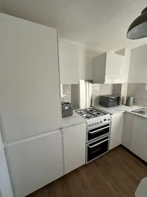 a white kitchen with a stove and a sink at Lochside Hub in Balloch