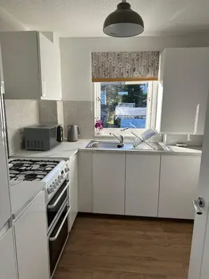 a kitchen with white cabinets and a sink and a window at Lochside Hub in Balloch