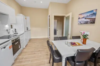 a kitchen and dining room with a white table and chairs at The Oban Apartment in Oban
