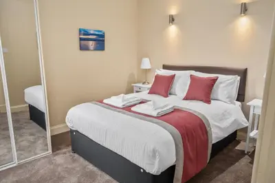a bedroom with a large bed with red pillows at The Oban Apartment in Oban