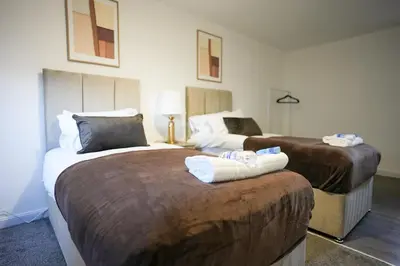 two beds in a hotel room with towels at Nigel House in Livingston