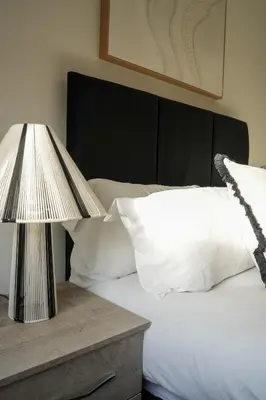 a bed with a table with a lamp on it at Nigel House in Livingston
