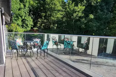a deck with chairs and a table and a mirror at 3 Bed House - Sea Views Balcony Parking Pets in Innellan