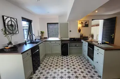 a large kitchen with white cabinets and black appliances at 3 Bed House - Sea Views Balcony Parking Pets in Innellan