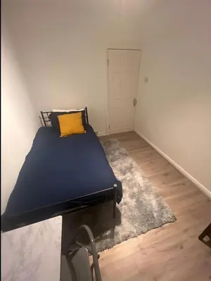 a bedroom with a bed with a yellow pillow on it at London Cozy Single Room in Moffat