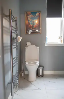 a bathroom with a toilet with a painting on the wall at 2-Bedroom Flat South Ayrshire in Troon
