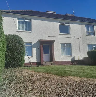 a white brick house with a blue door at 2-Bedroom Flat South Ayrshire in Troon
