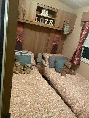 two teddy bears sitting on two beds in a room at Static Caravan 8 Berth 3 bedrooms, ensuite Saltcoats, Ayrshire, Scotland DG CH in Saltcoats