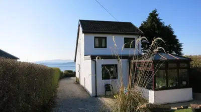 a small white house with a black roof at An Cala in Connel