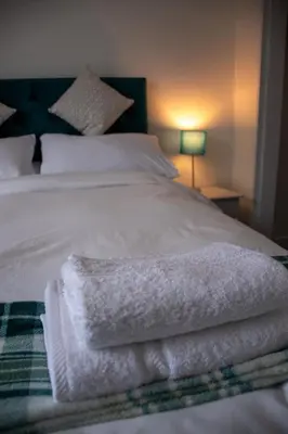 a bed with white sheets and towels on it at Island View in Campbeltown