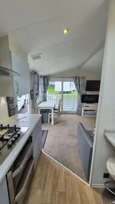a kitchen and living room with a stove and a table at Caravan Bliss in Minishant