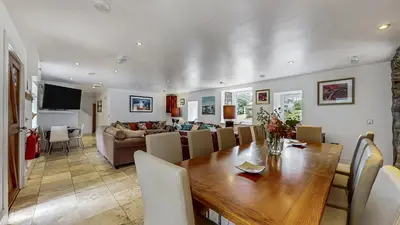 a dining room and living room with a wooden table at Finest Retreats - Old Barn at Ormidale House in Clachan of Glendaruel
