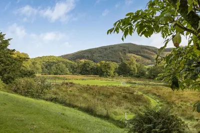 a view of a field with a mountain in the background at Finest Retreats - Old Barn at Ormidale House in Clachan of Glendaruel