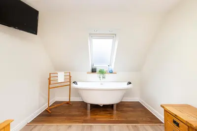a white bath tub in a bathroom with a window at JOIVY Lovely Flats in Edinburgh City Centre in Edinburgh