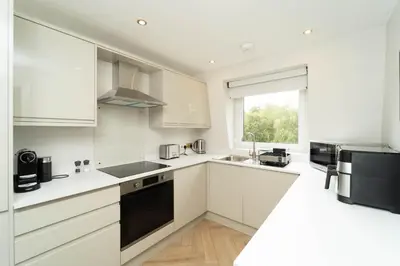 a white kitchen with white cabinets and a window at Eagleside Apartments in Auchterarder