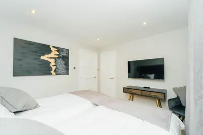 a white bedroom with a bed and a tv at Eagleside Apartments in Auchterarder