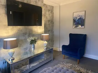 a living room with a tv and a blue chair at 3BR Sleeps 6 Free Parking Near Glasgow City Centre in Renfrew