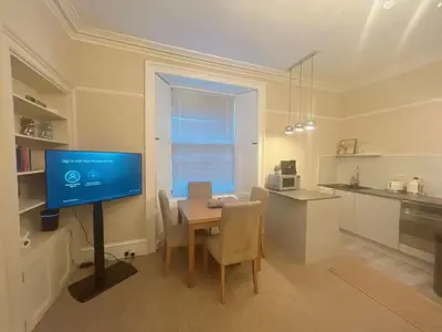 a dining room with a table with a tv and a kitchen at Adorable 2BR Apartment in Edinburgh
