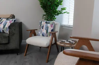 a living room with two chairs and a table at Vacant Nests Ivy Cottage 3BR Wi-Fi in Kilsyth