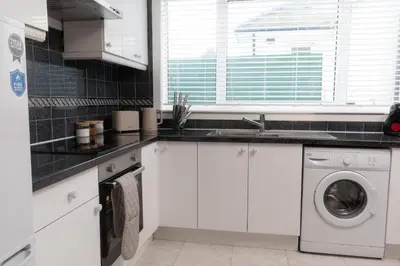 a white kitchen with a sink and a dishwasher at Vacant Nests Ivy Cottage 3BR Wi-Fi in Kilsyth