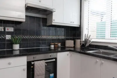 a kitchen with white cabinets and a sink at Vacant Nests Ivy Cottage 3BR Wi-Fi in Kilsyth
