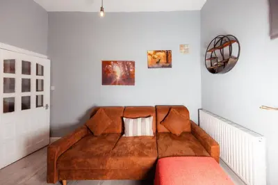 a large brown couch in a room with white walls at Central Apartment by the Meadows 9 in Edinburgh