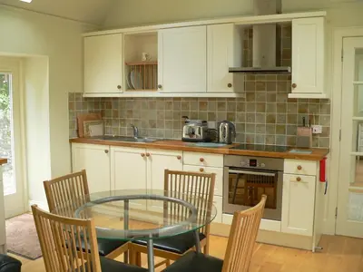 a kitchen with a glass table and chairs and a counter at Burn Cottage - A Secluded Highland Retreat For Two in Fortingall