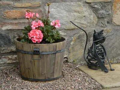 a wooden planter with pink flowers and a cat statue at Burn Cottage - A Secluded Highland Retreat For Two in Fortingall