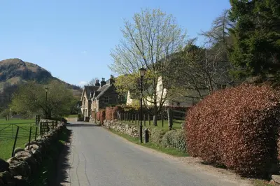 a road leading to a house with a stone fence at Burn Cottage - A Secluded Highland Retreat For Two in Fortingall