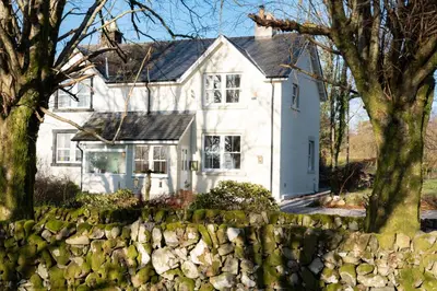 a white house with a stone wall in front of it at Craignair in Castle Douglas