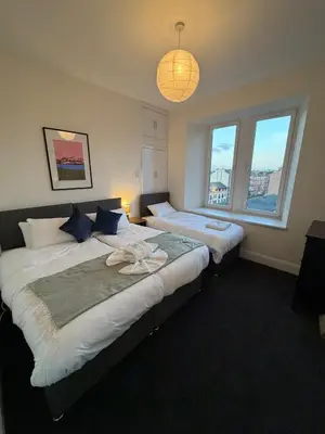 two beds in a room with two windows at Spacious Tenement with free parking in Glasgow