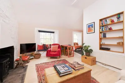 a living room with a fireplace and a red chair at Chic 1-Bedroom Apartment in Edinburgh New Town in Edinburgh