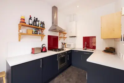 a kitchen with blue cabinets and white counter tops at Chic 1-Bedroom Apartment in Edinburgh New Town in Edinburgh