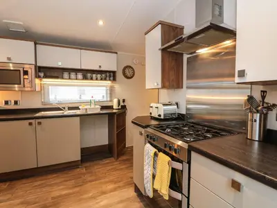 a kitchen with white cabinets and a stove top oven at Loch Lomond Holiday home in Arrochar
