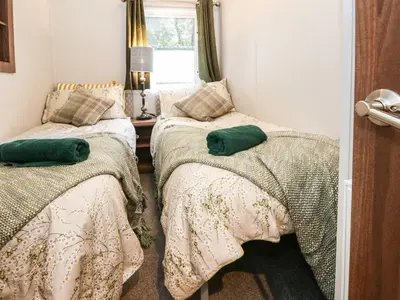 a bedroom with two beds with green pillows on them at Loch Lomond Holiday home in Arrochar