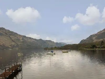 a lake with two boats in the water and mountains at Loch Lomond Holiday home in Arrochar