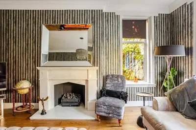 a living room with a fireplace and a chair at Edwardian Manor hot tub & Pool in Glasgow, Gated in Giffnock