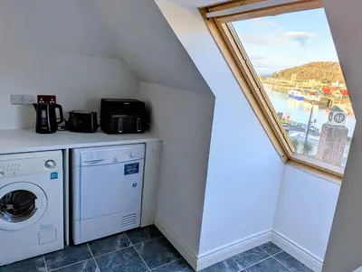a laundry room with a window and a washing machine at Littlebay Penthouse in Oban