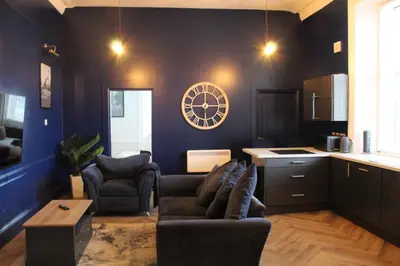 a living room with two chairs and a clock on the wall at 89A Bank Street 3 bedroom in Jamestown