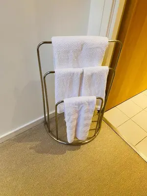 a metal towel rack with three white towels on it at Cozy Room in Glasgow in Glasgow