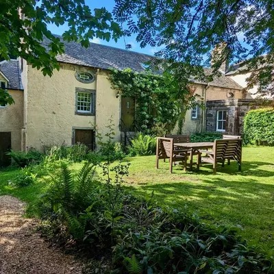 a house with a table and benches in the yard at Estate Getaway at Powis House Estate in Stirling