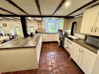 a large kitchen with white cabinets and a brick wall at Estate Getaway at Powis House Estate in Stirling