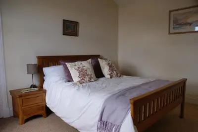 a bed with white sheets and pillows on it in a bedroom at Inveree in Oban