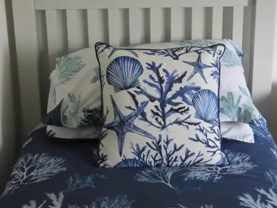 a bed with a blue and white pillow with seashells at Inveree in Oban