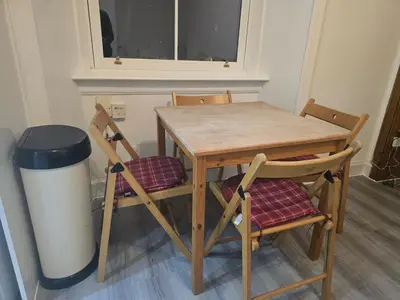 a wooden table with two chairs and a trash can at Comfy Semi-Central Stay near Entertainment Park in Edinburgh