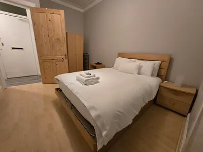 a bedroom with a large bed with white sheets at Comfy Semi-Central Stay near Entertainment Park in Edinburgh