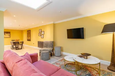 a living room with a pink couch and a tv at Dragon Suites Luxury Apartments at Rutland Square in Edinburgh