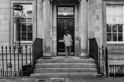 a person walking into a door of a building at Dragon Suites Luxury Apartments at Rutland Square in Edinburgh